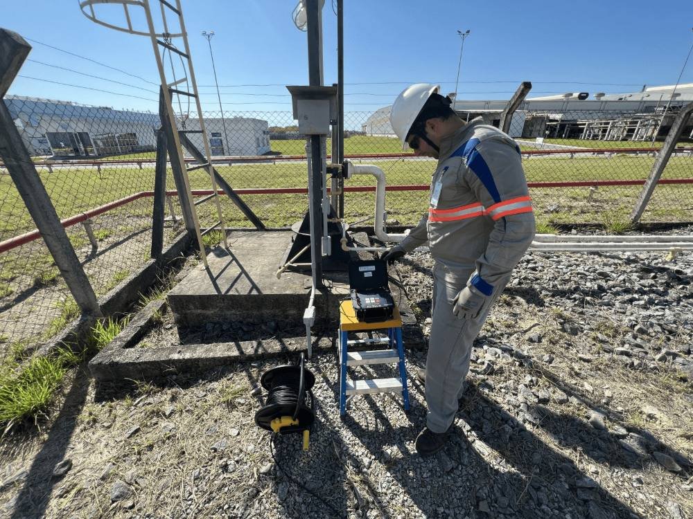 Eletricista fazendo medição de aterramento em campo, com instrumento e carretel de cabo
